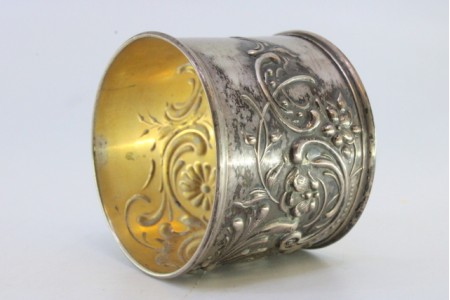 Argola de guardanapo em prata com motivos florais relevados envolvendo cartela para monograma.